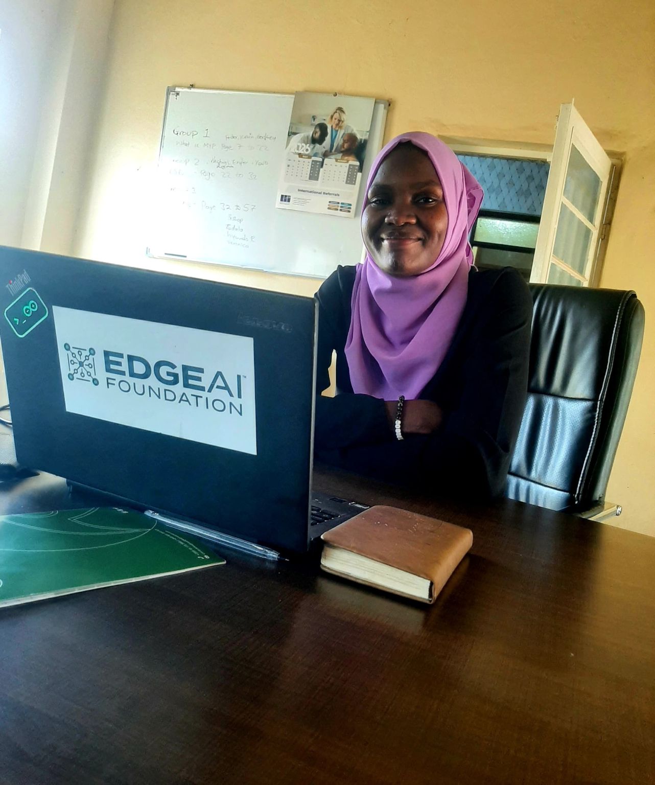 Matilda, FemAnalytica intern at YouthWave, smiling at a desk with a laptop.